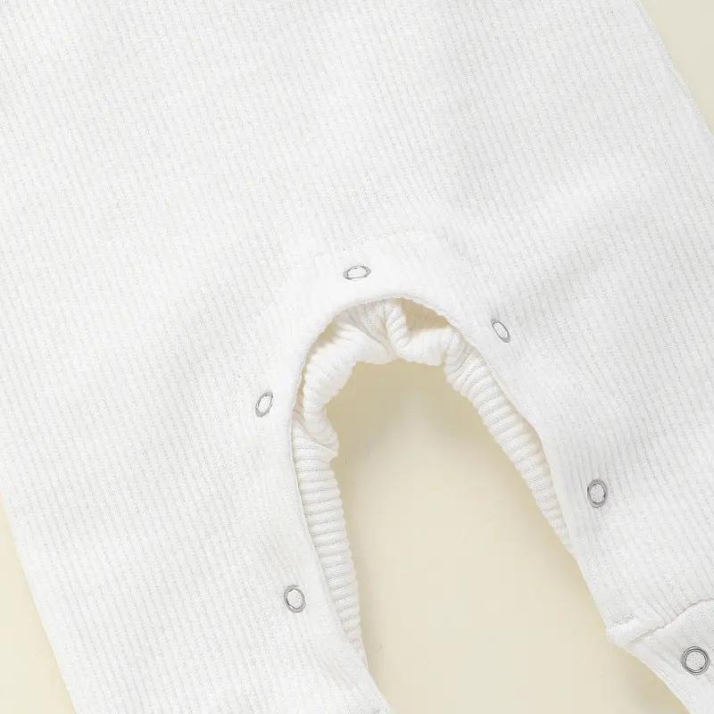 This adorable long sleeve ruffle romper features ribbed fabric with ruffled shoulders and wooden button accents, perfect for baby's cute and comfy style. A&S Collection