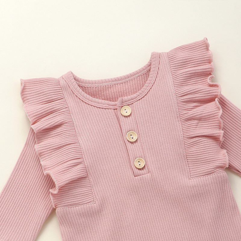 This adorable long sleeve ruffle romper features ribbed fabric with ruffled shoulders and wooden button accents, perfect for baby's cute and comfy style. A&S Collection