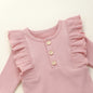 This adorable long sleeve ruffle romper features ribbed fabric with ruffled shoulders and wooden button accents, perfect for baby's cute and comfy style. A&S Collection